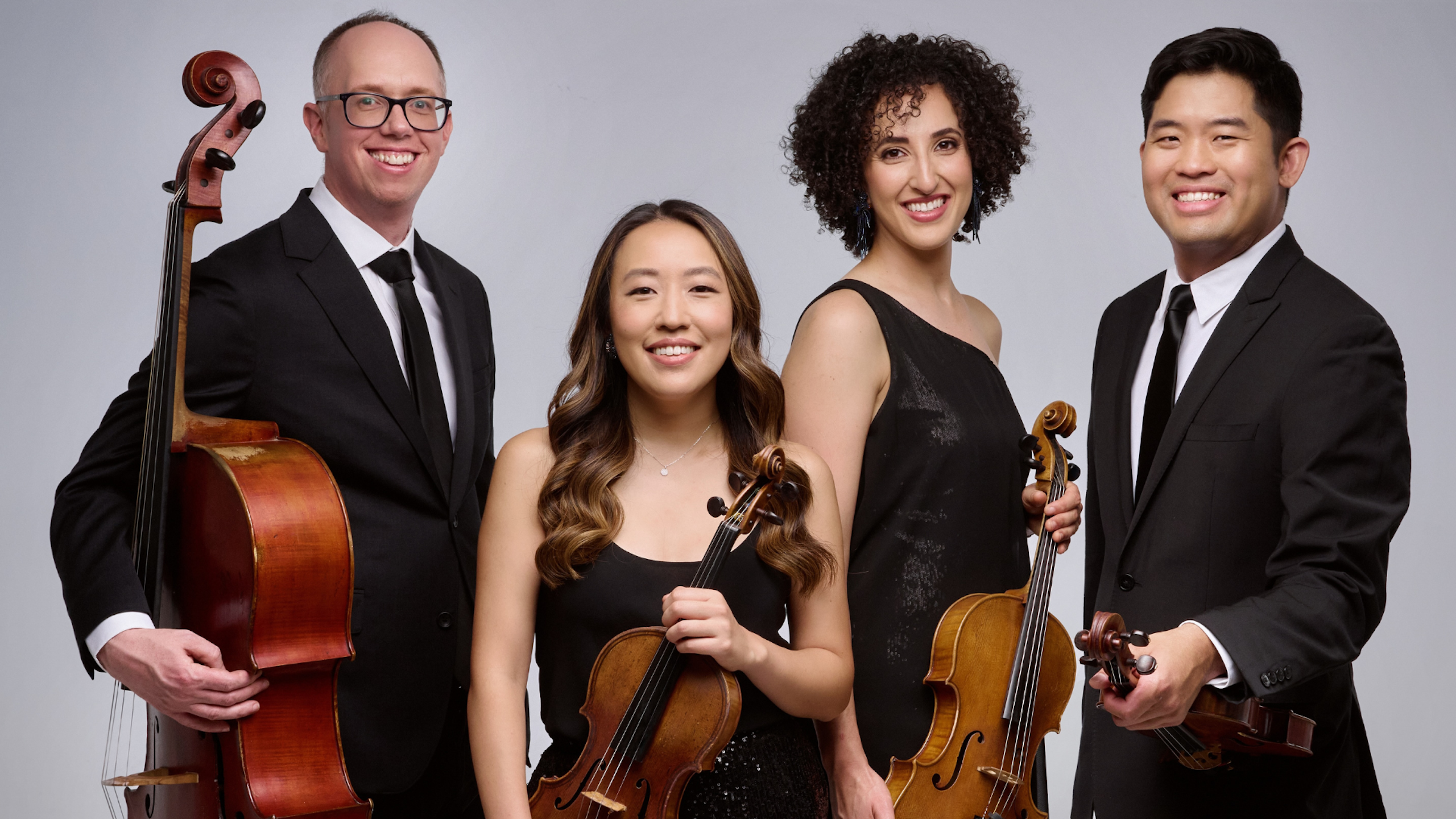 A quartet of musicians hold a cello, two violins, and a viola.