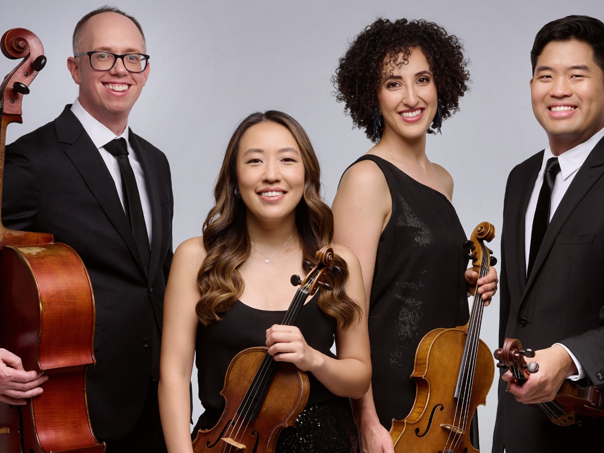 A quartet of musicians hold a cello, two violins, and a viola.