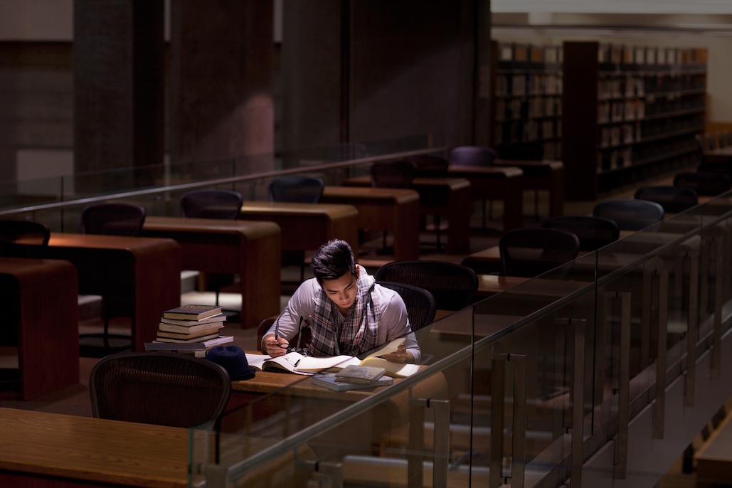 A student studies alone in a dark library