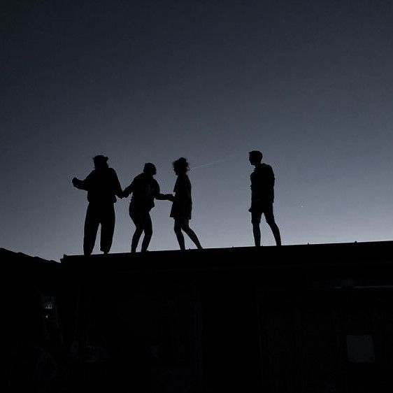 Silhouettes of four people on a rooftop at sunset representing a strategic team