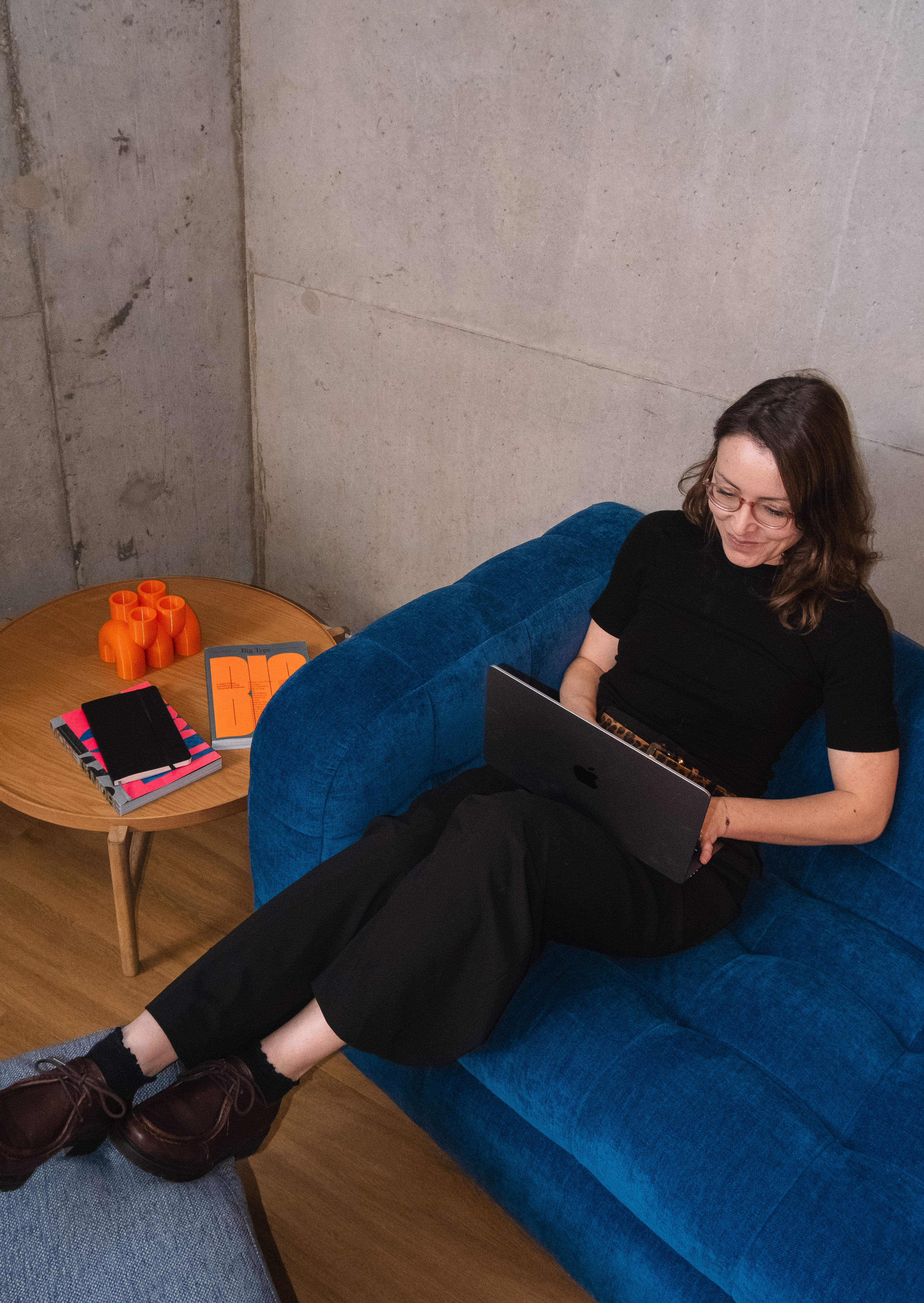 Lady working on her computer, sitting in a blue couch in BuzzBrothers' offices in Geneva.