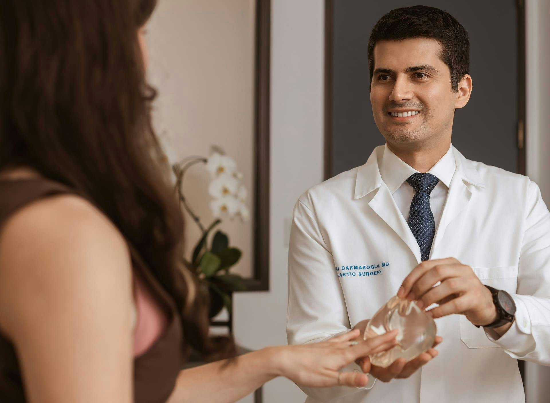Dr. Cagri Cakmakogul showing patient a breast implant