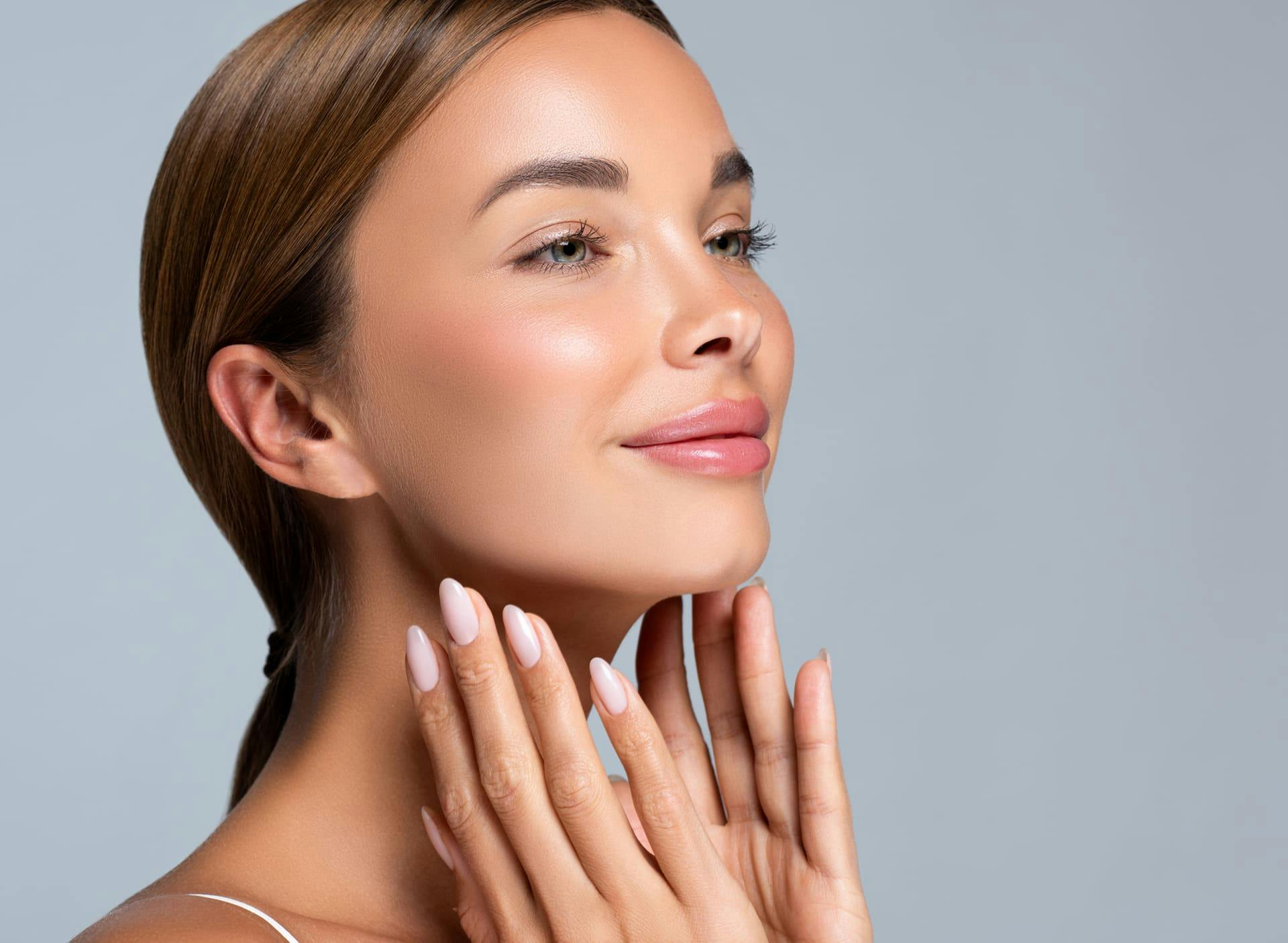 woman smiling and touching her jaw with low ponytail