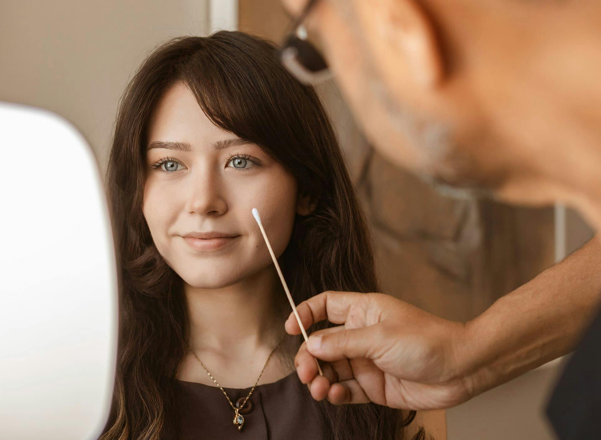 Dr. Munish Batra examining patient while she holds a handheld mirror