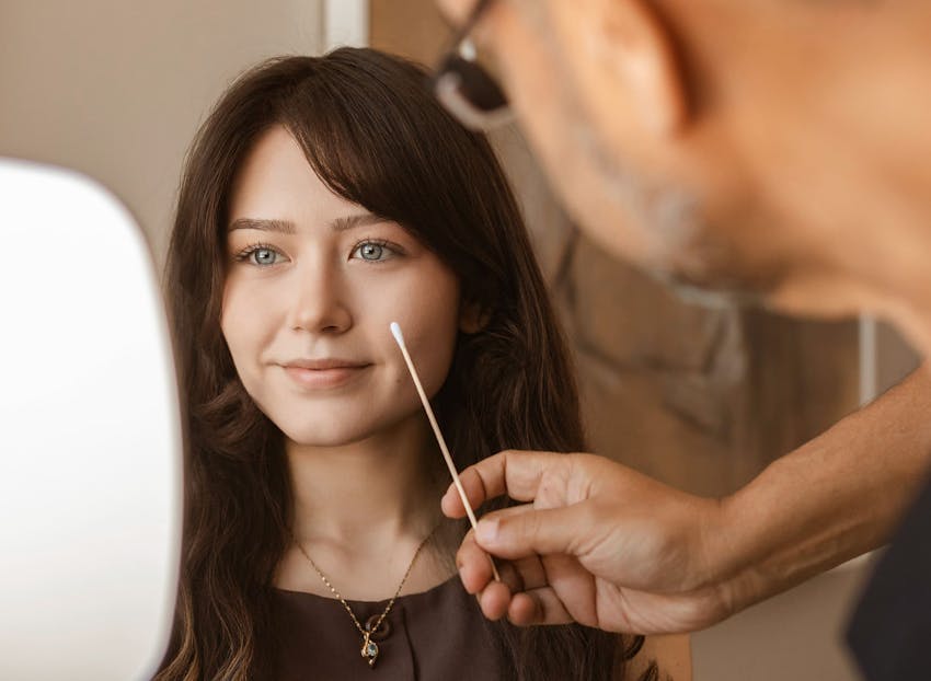 Dr. Munish Batra examining patient while she holds a handheld mirror