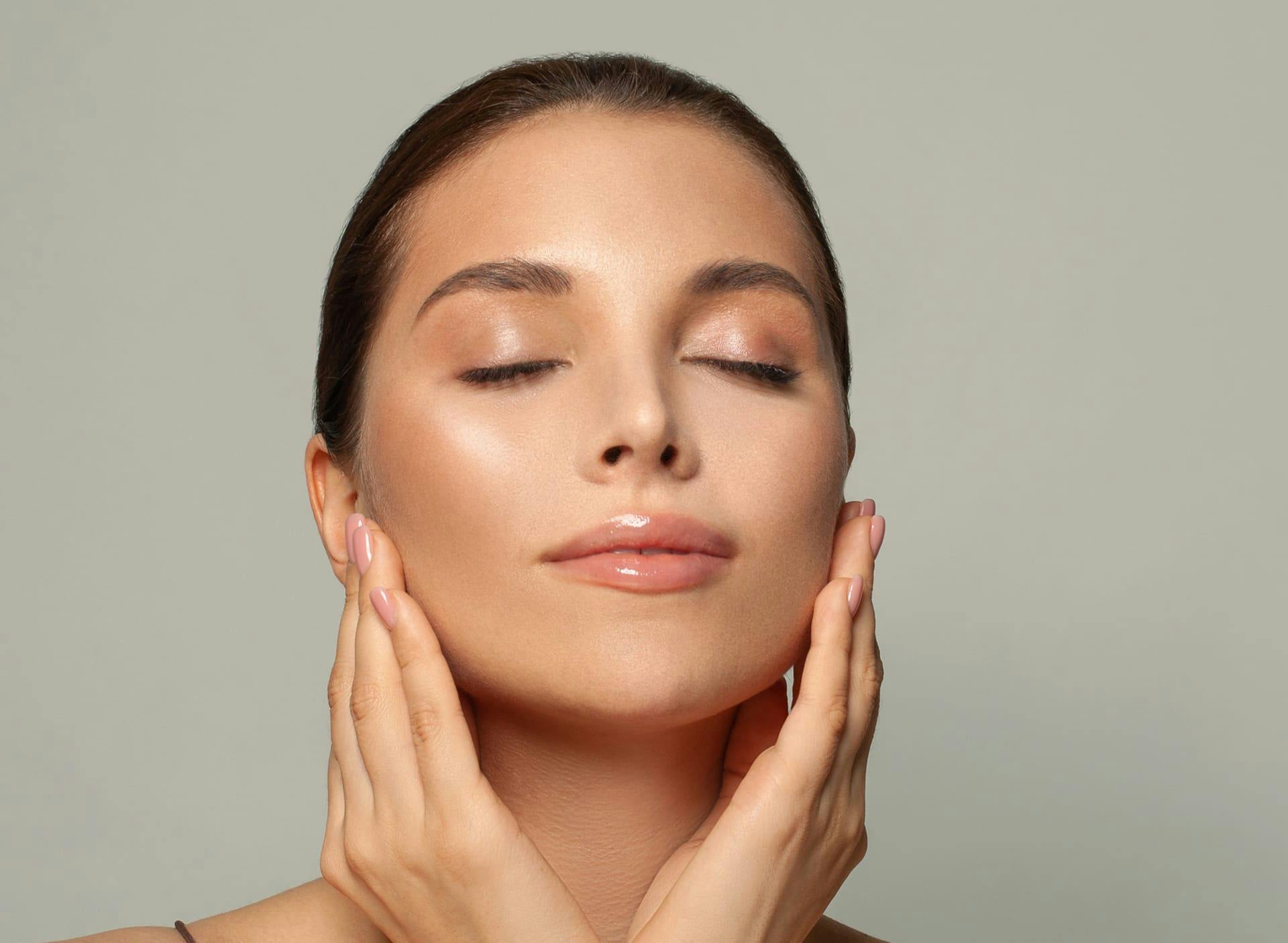 woman touching her jaw with her eyes closed