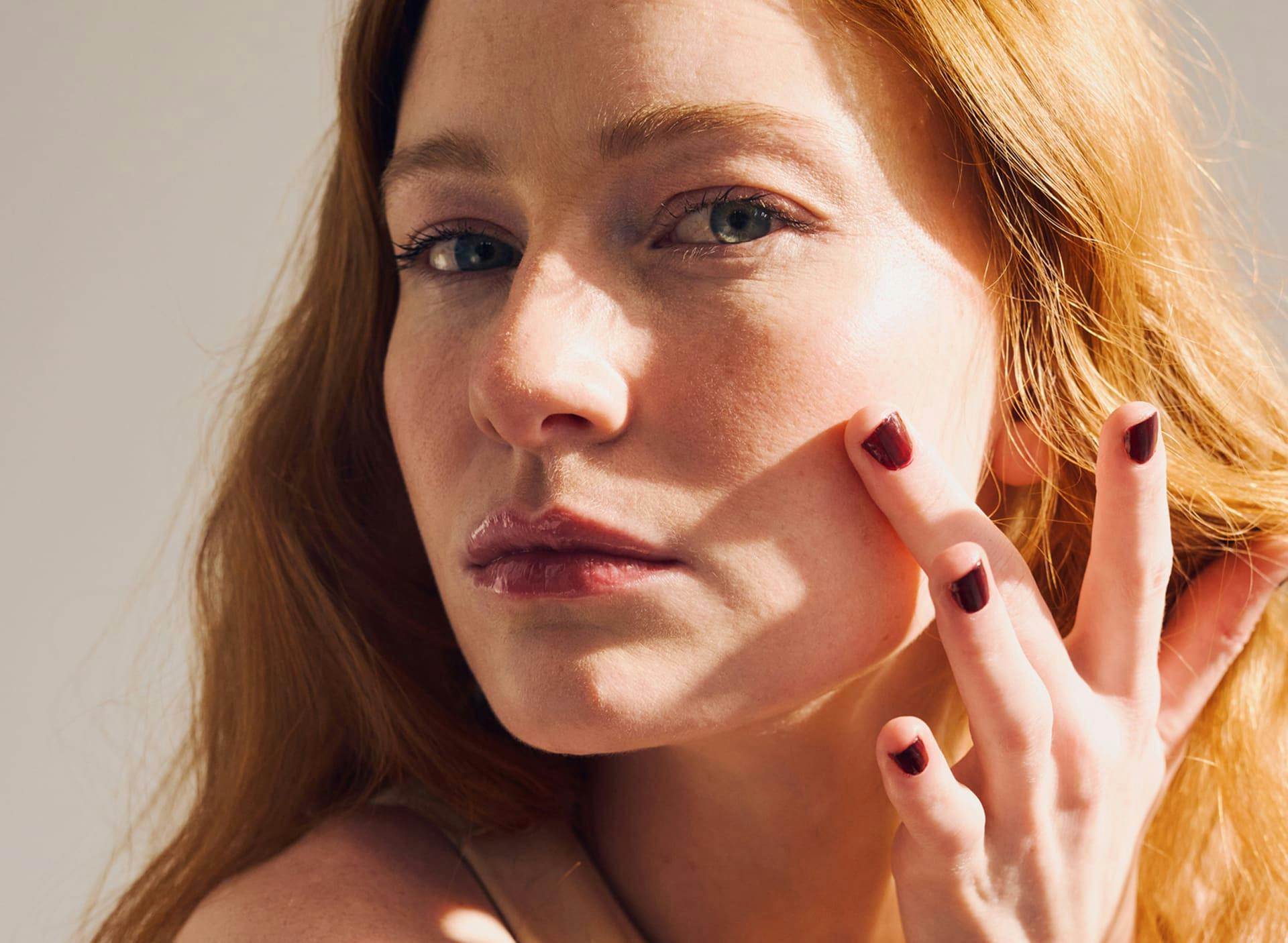 woman touching her cheek with sunlight on the right side of her face