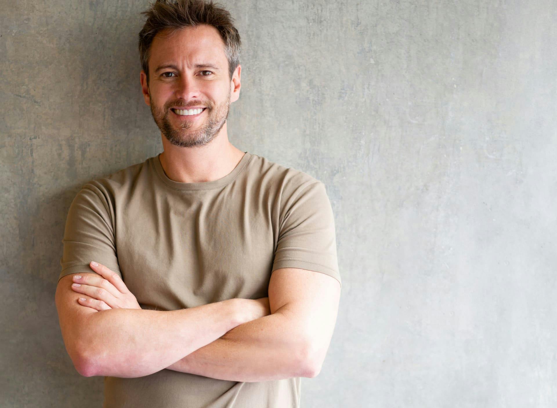 man leaning against wall with his arms crossed