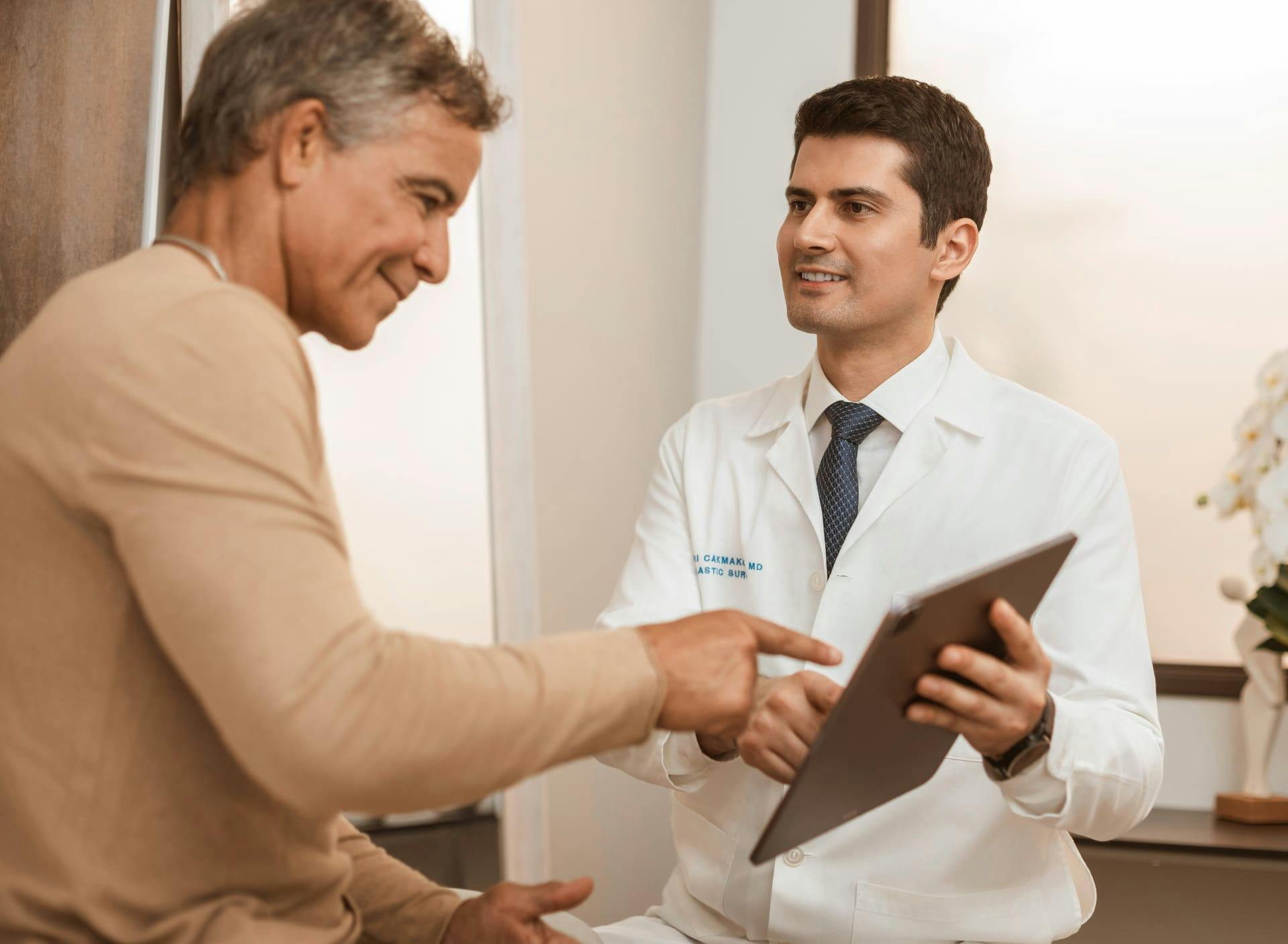Dr. Cagri Cakmakogul showing male patient a clipboard