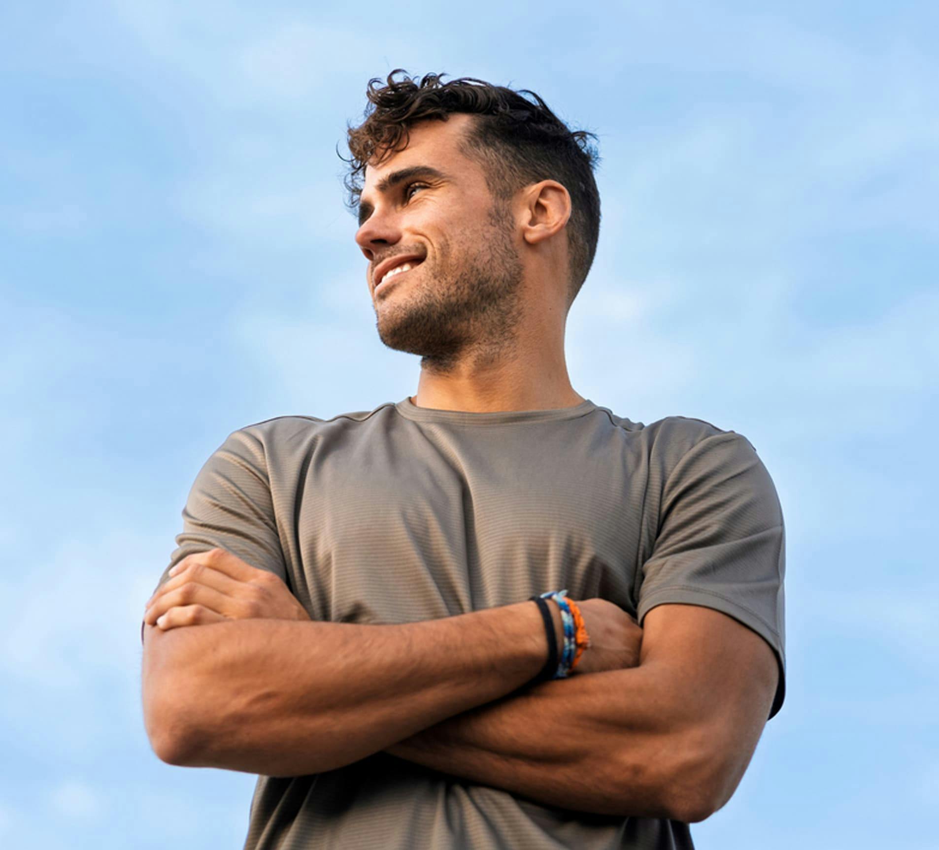 man smiling and crossing his arms in grey shirt
