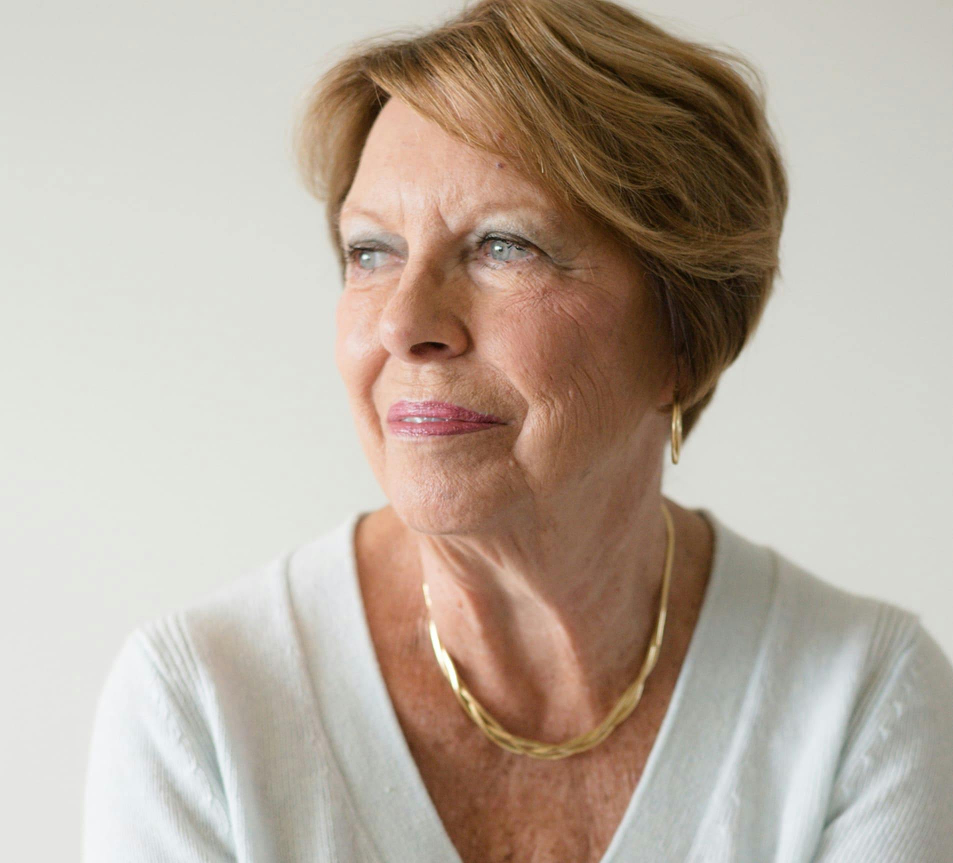 older woman looking to the left in white sweater