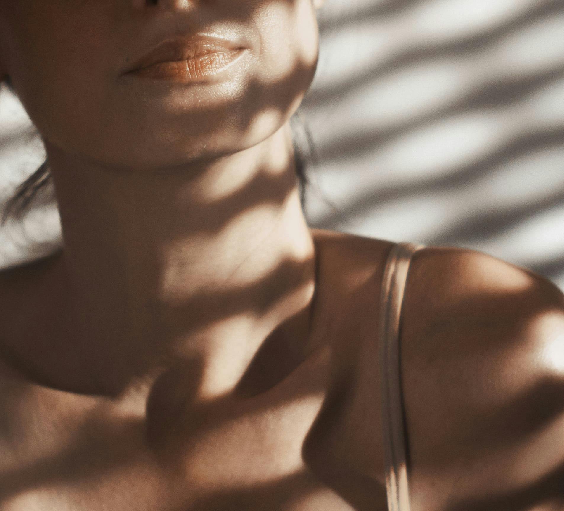 woman's neck area with blinds blocking the sunlight