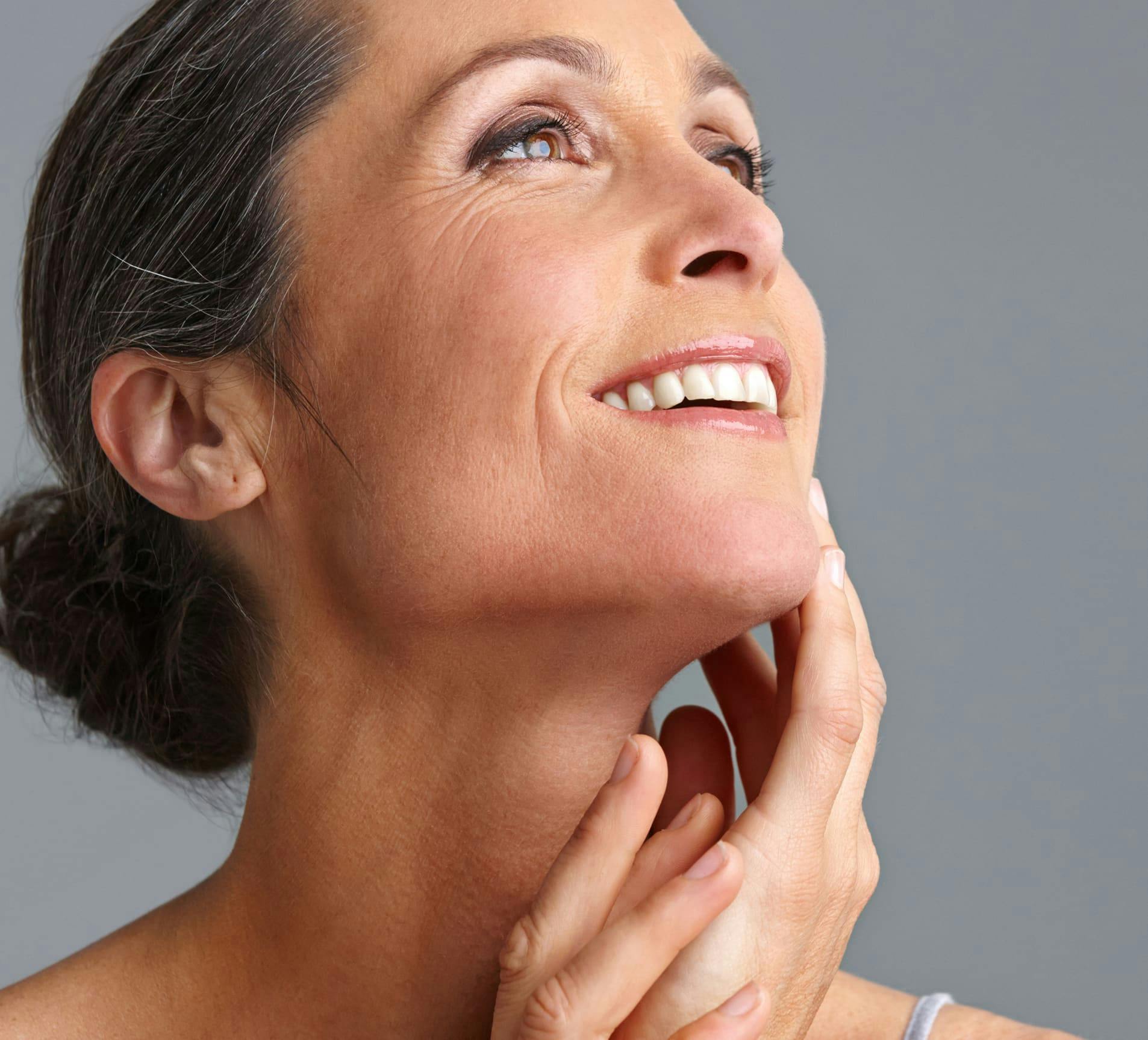 woman smiling and looking up with hair tied in a bun