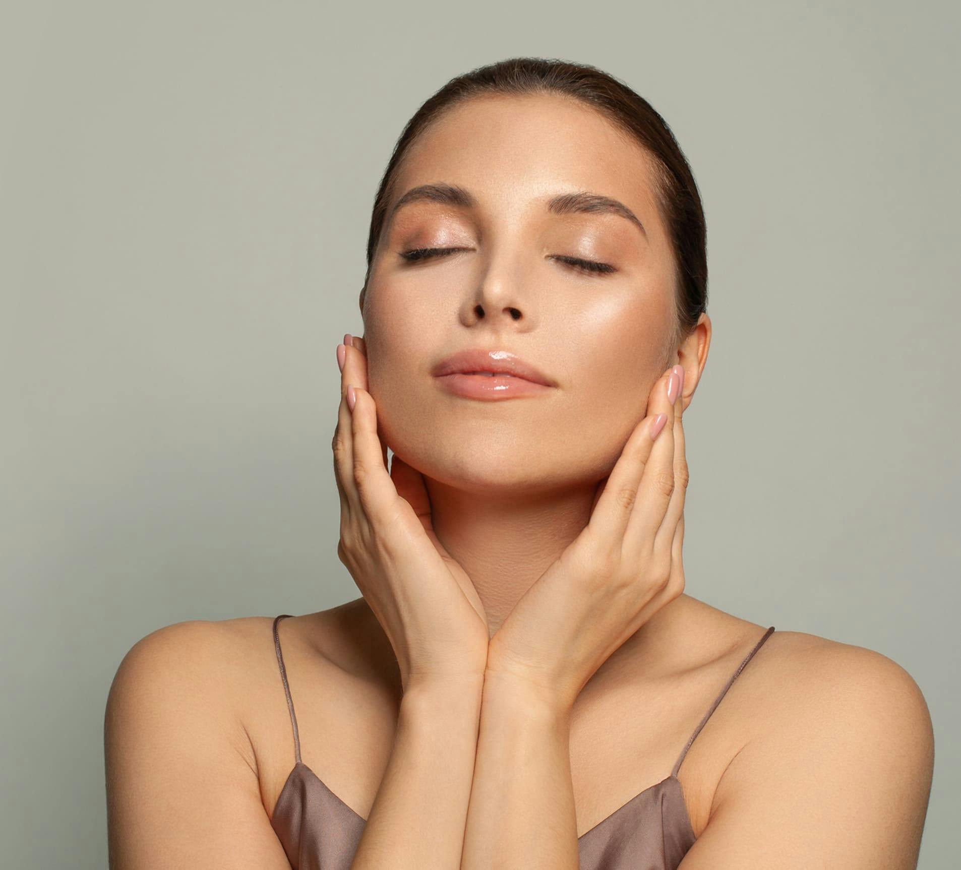 woman with her eyes closed touching her face