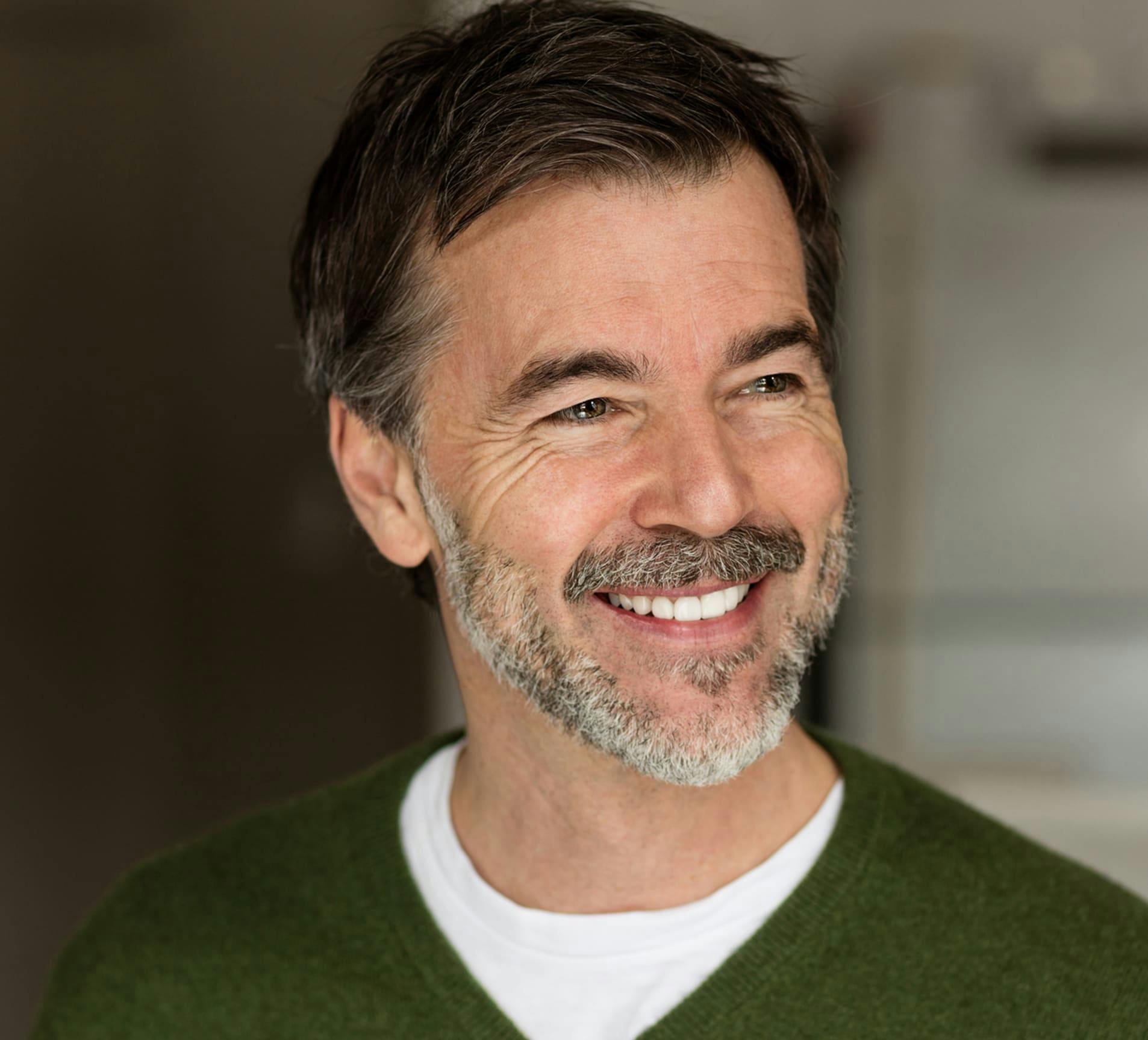 man smiling in green sweater