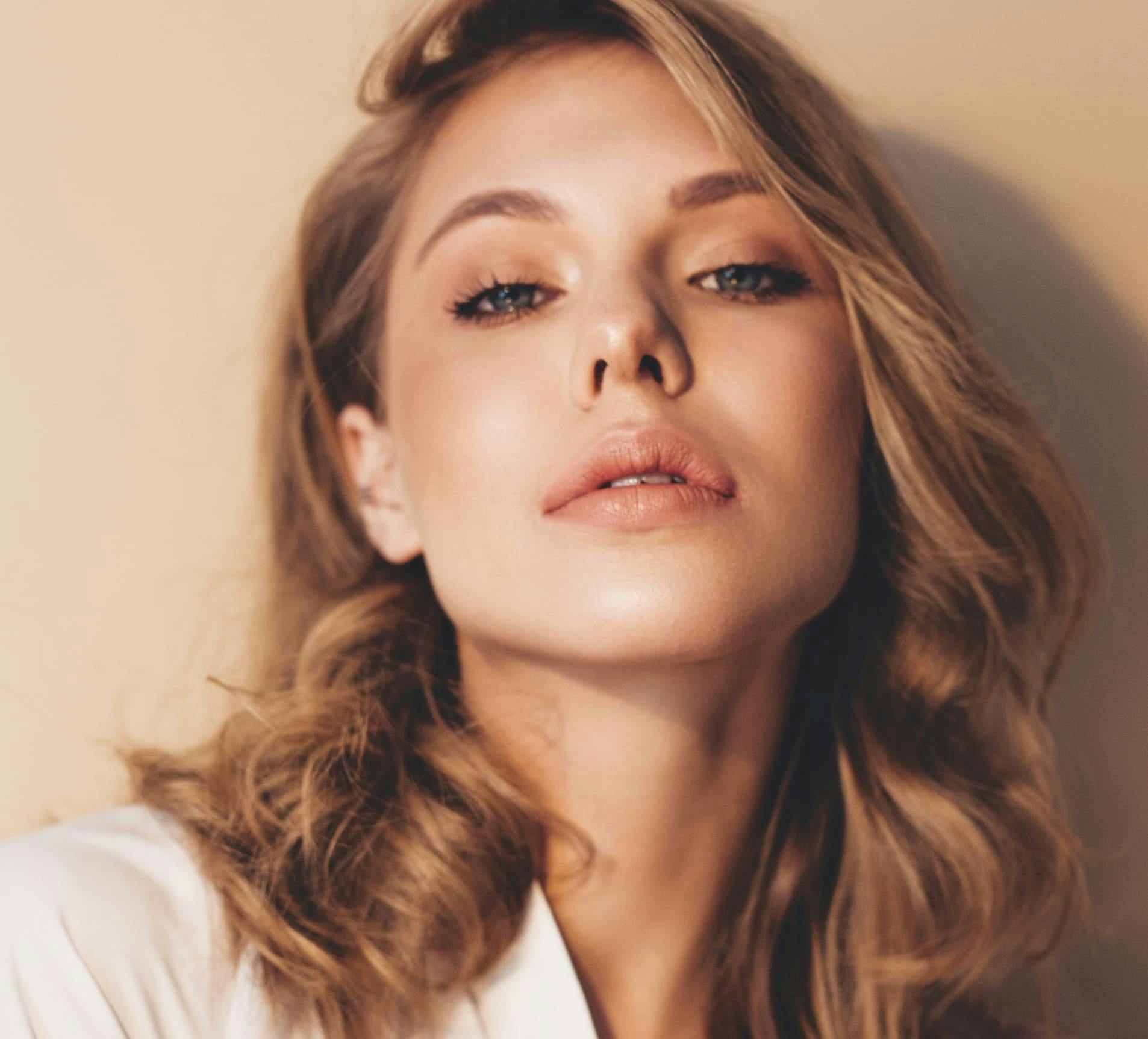 woman with wavy hair looking forward with her head tilted up
