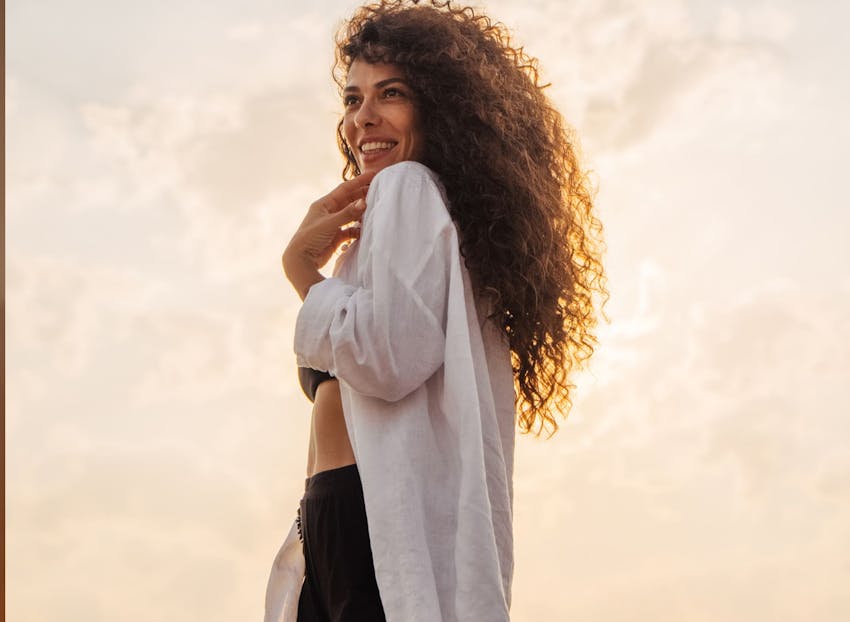woman with big curly hair in over sized white top