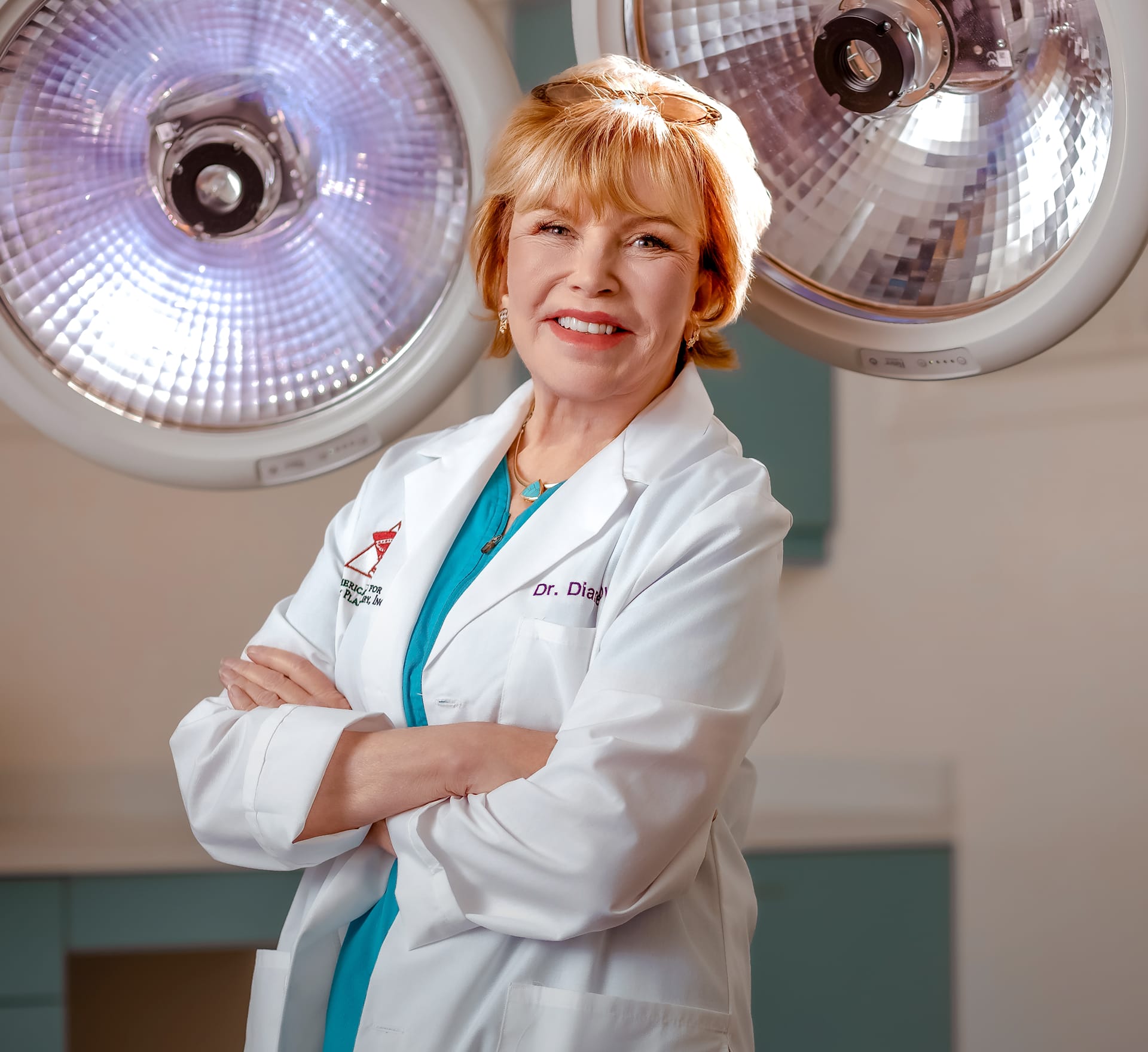 Dr Diane Duncan with arms crossed in front of her wearing white lab coat and blue scrubs
