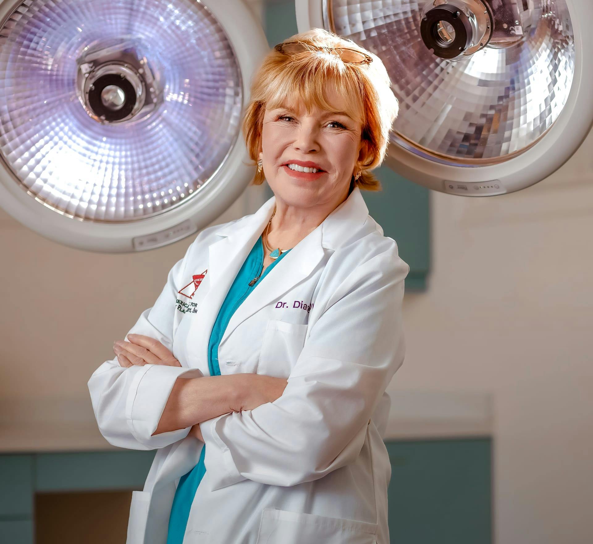 Dr Diane Duncan with arms crossed in front of her wearing white lab coat and blue scrubs