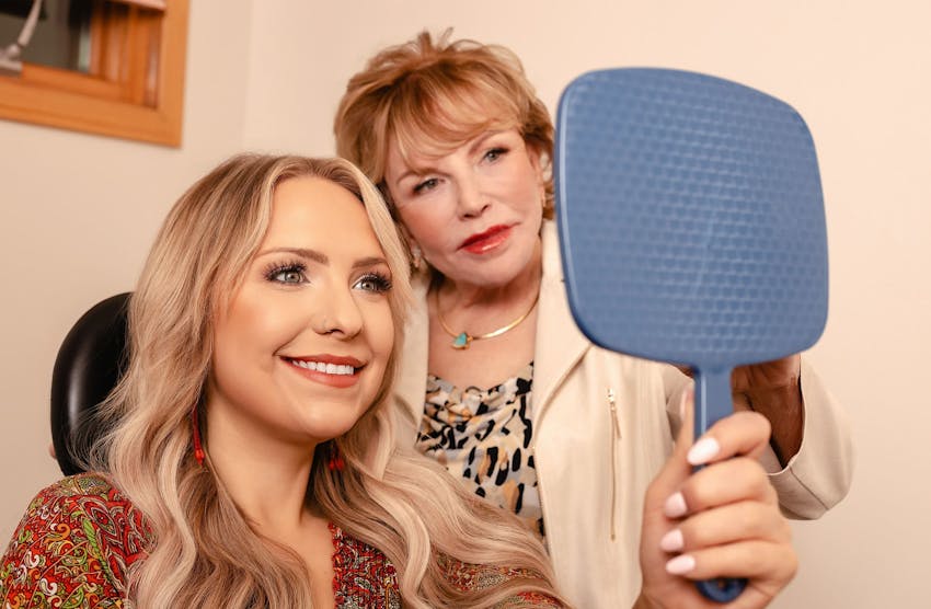 Dr. Duncan looking in handheld mirror with patient