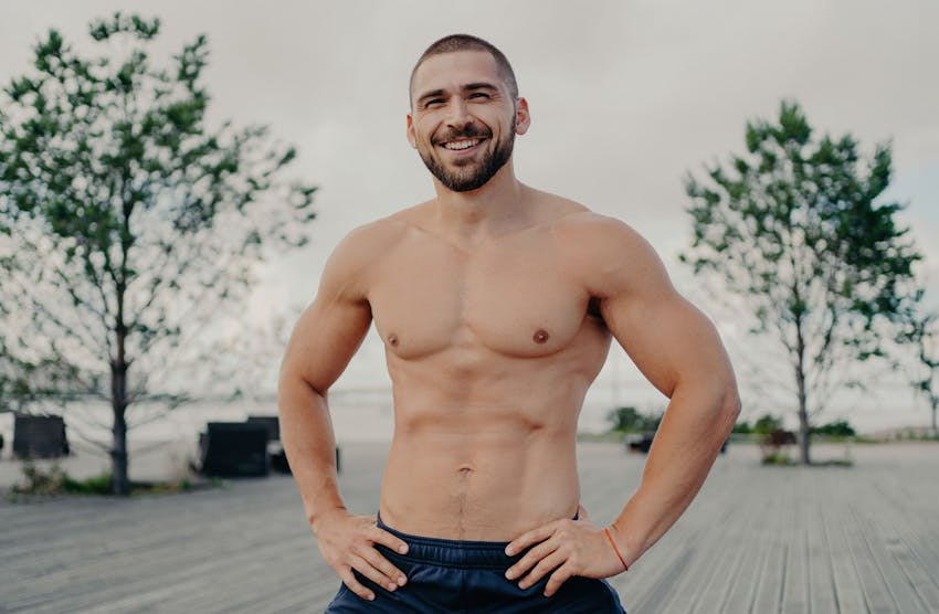 man smiling shirtless with his hands on his hips
