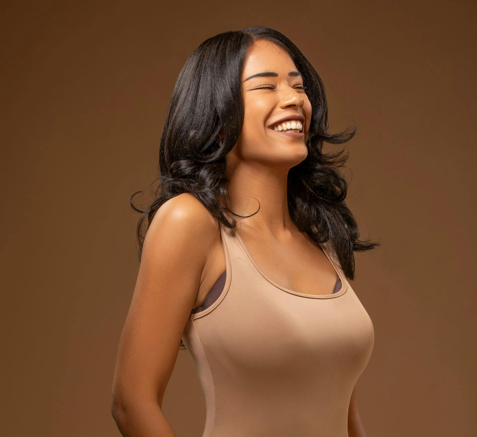 woman smiling in beige bodysuit