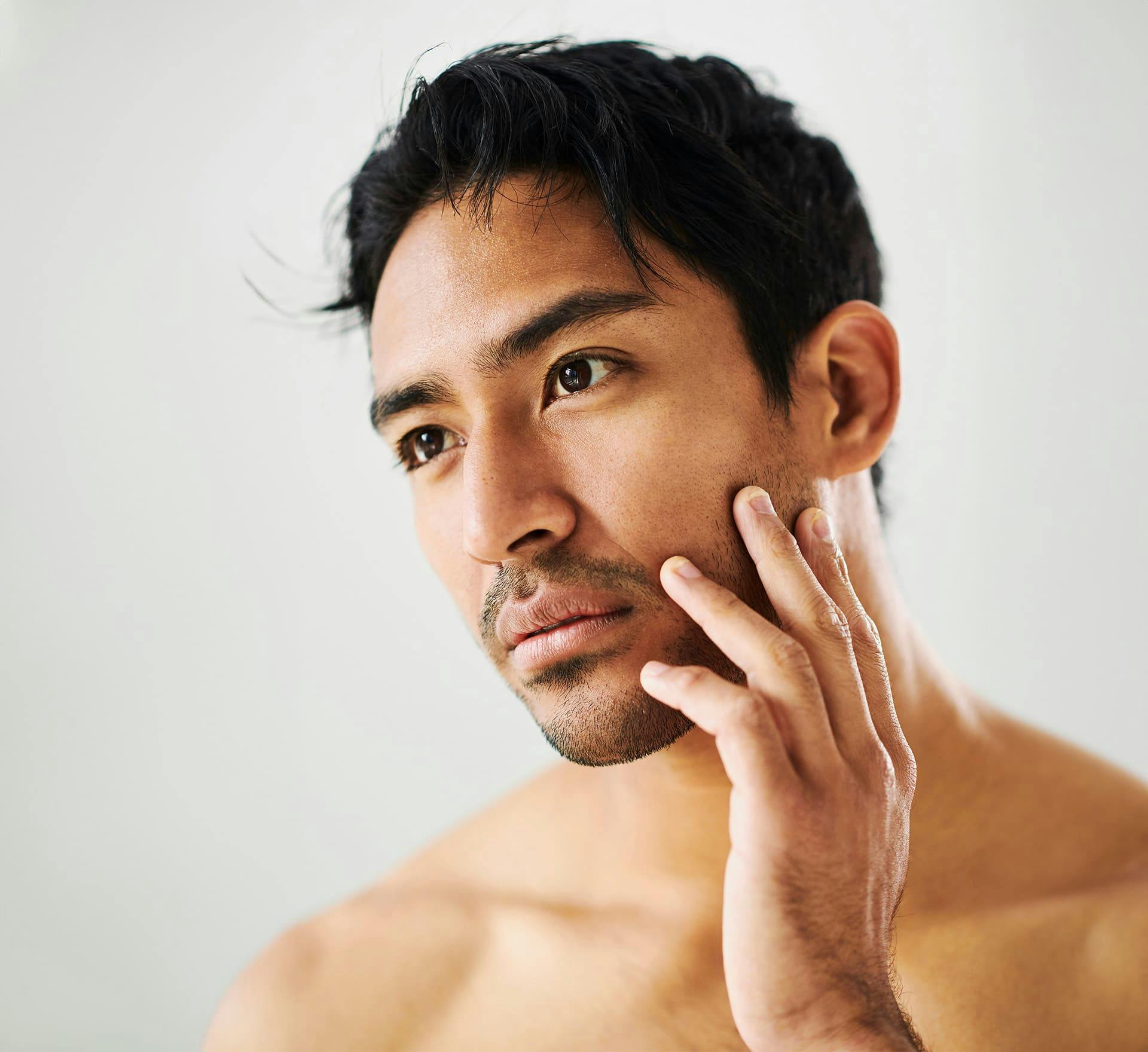 man touching the side of his cheek and jaw