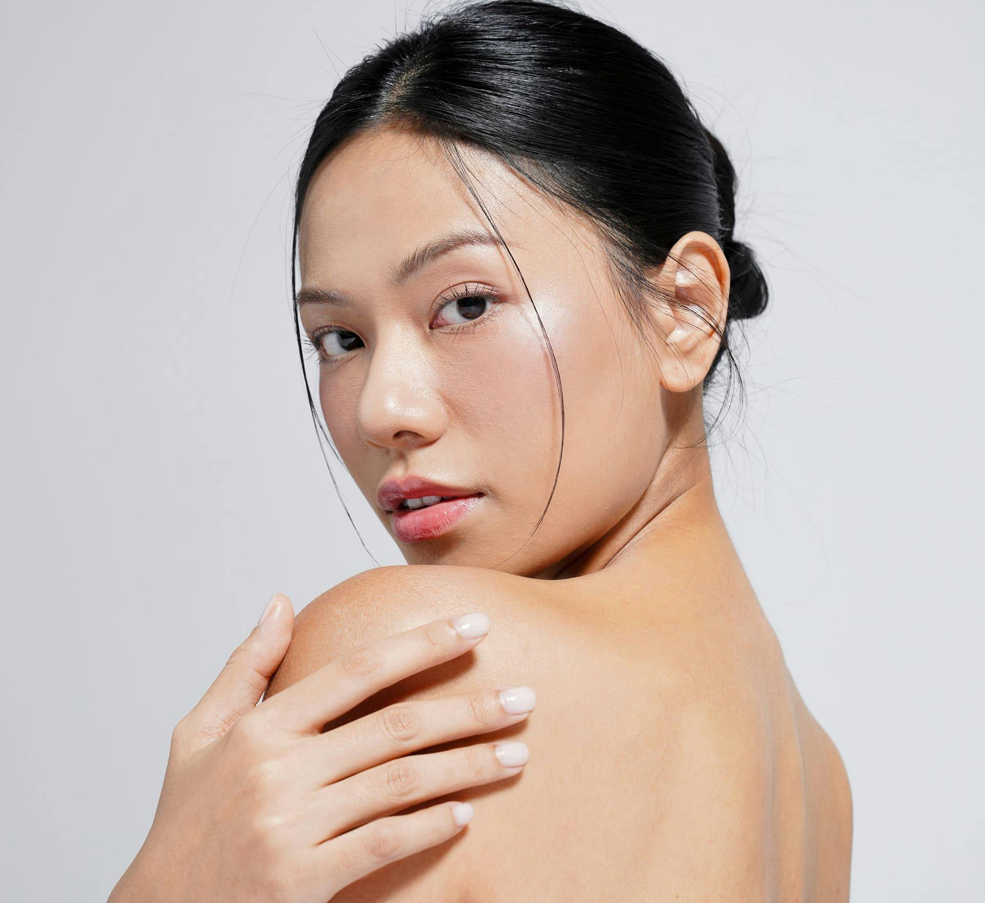 woman looking over her shoulder with her hand touching it