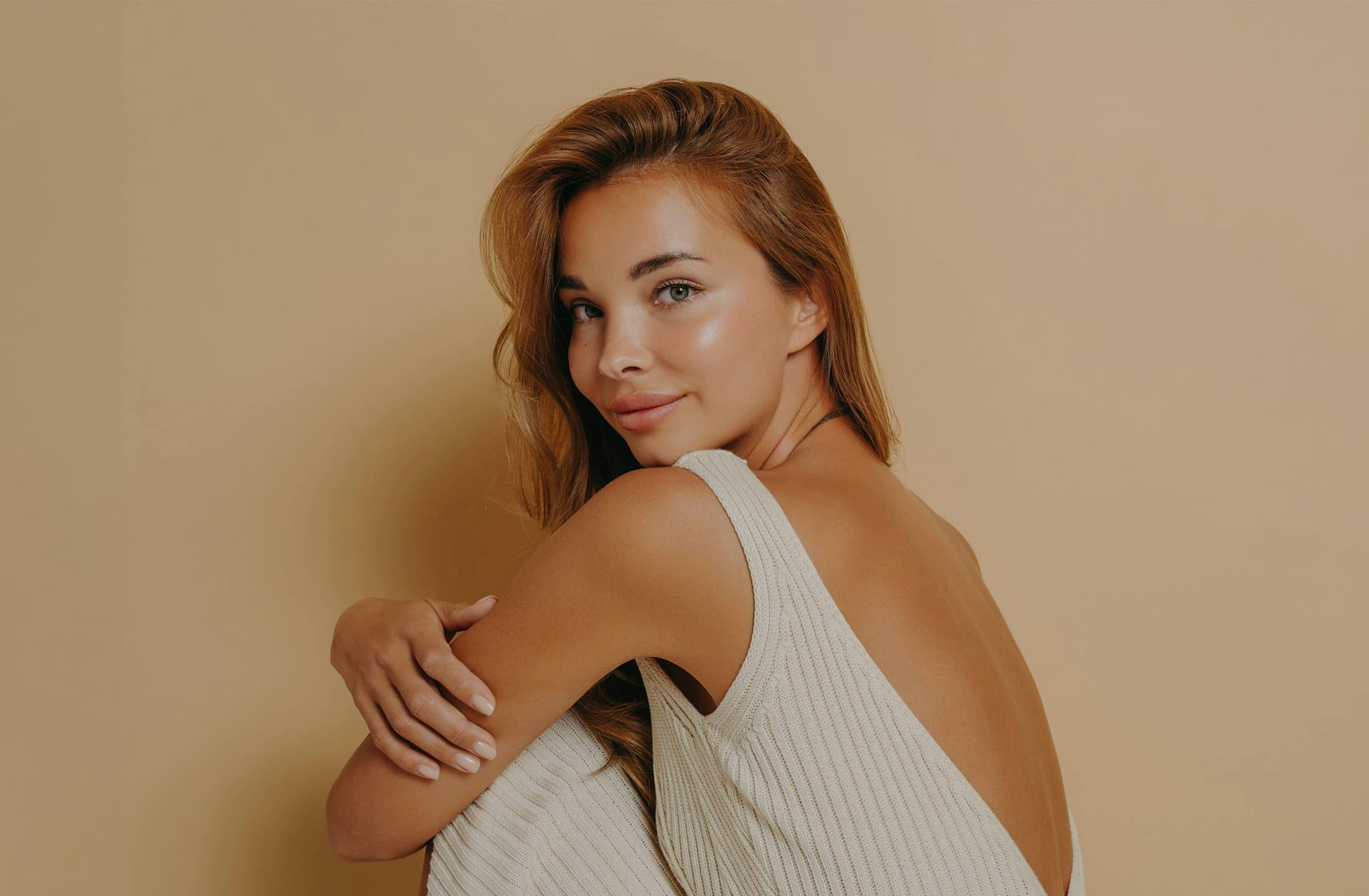 woman looking over her shoulder and smiling while hugging her knees