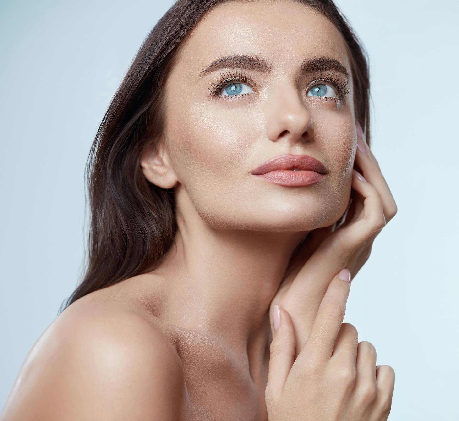 woman with blue eyes looking upwards with her hand near her ear