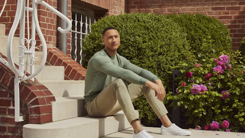 man with a green shirt and beige pants sitting smiling