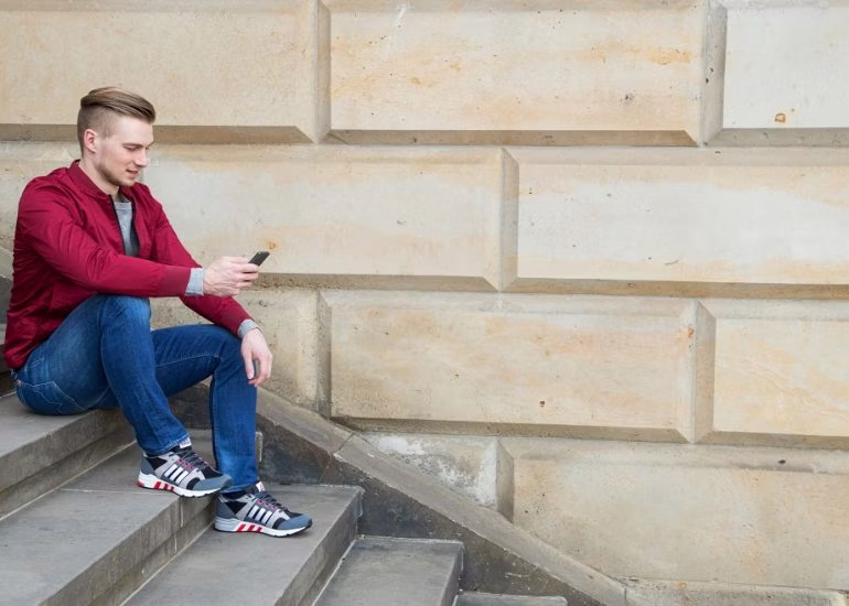 person, sitting, footwear, shoe, boy, male, teen, pants, sneaker, mobile phone