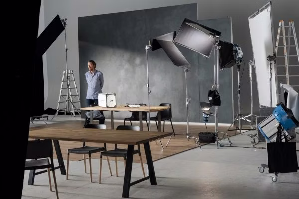 person, chair, furniture, bag, handbag, desk, box, indoors, electronics, camera