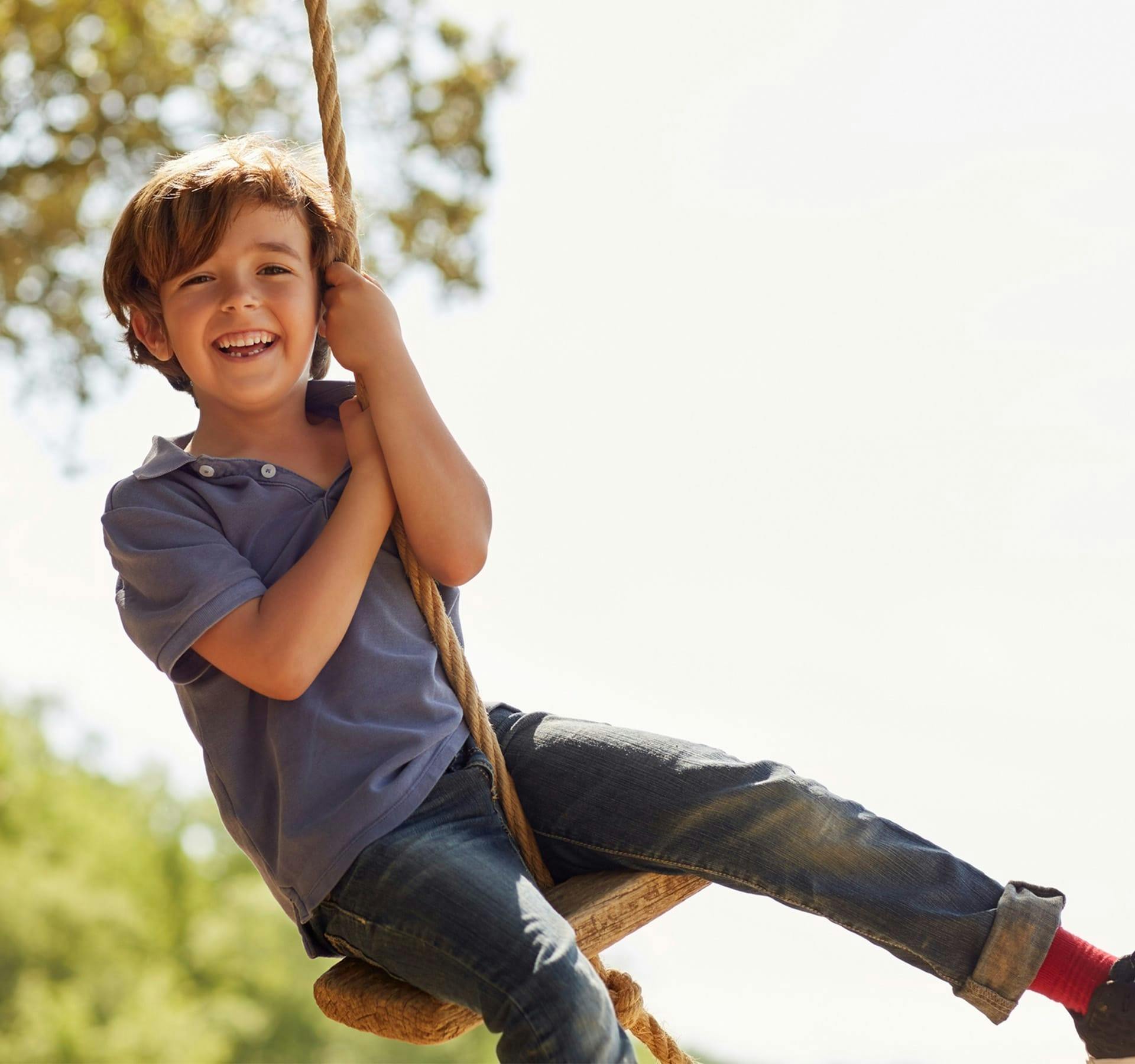 little boy swinging on a rope swing