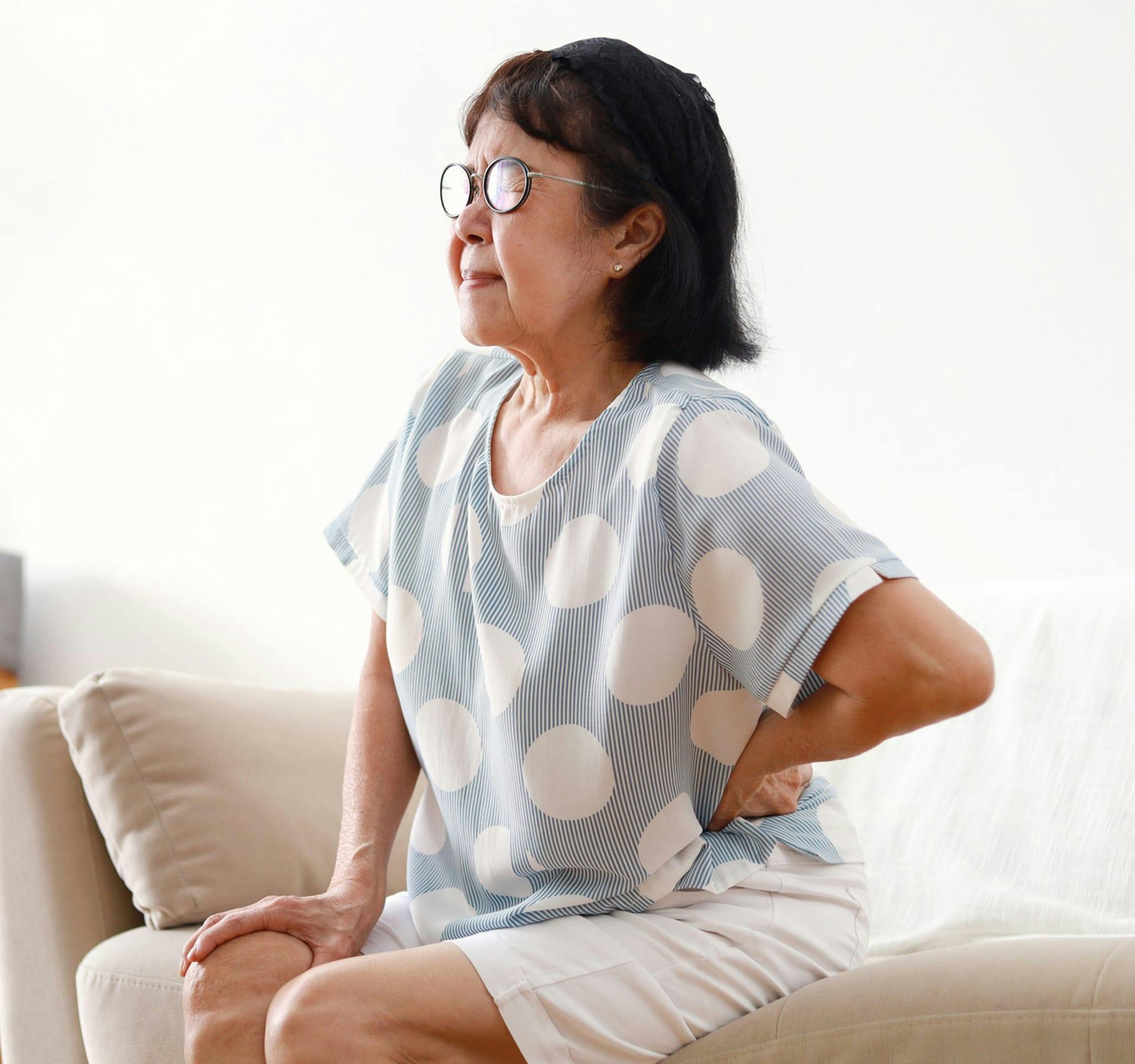older woman holding her lower back in pain