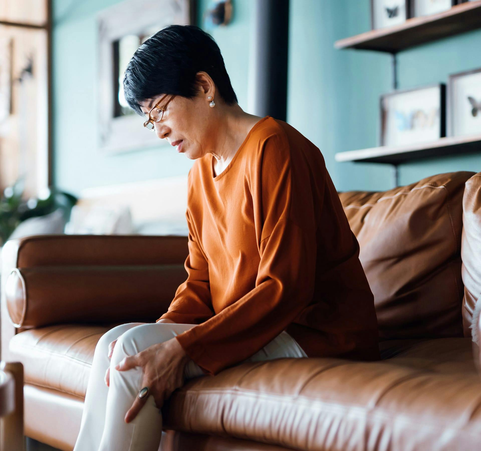 woman sitting on a couch holding her leg in pain