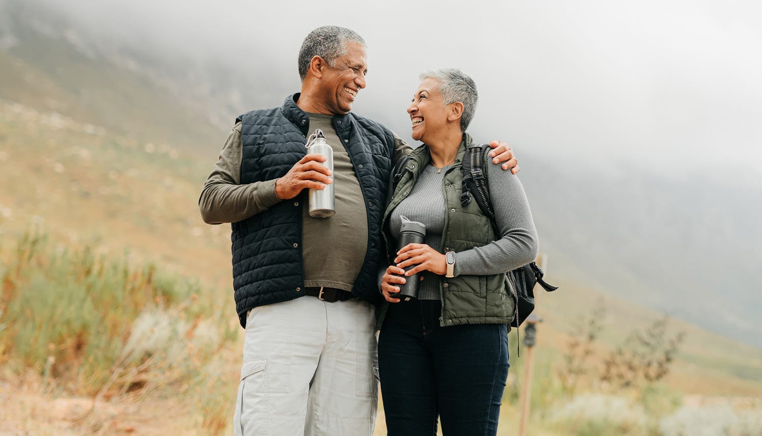 older man and woman standing together on a hill