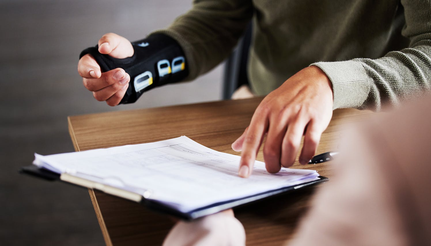man in a cast pointing to a clipboard