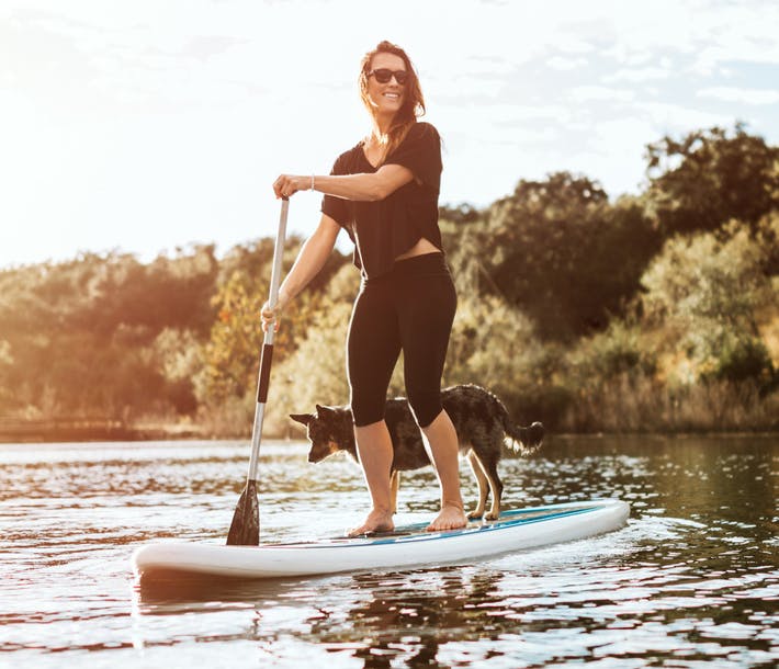A woman paddlebaording with her dog