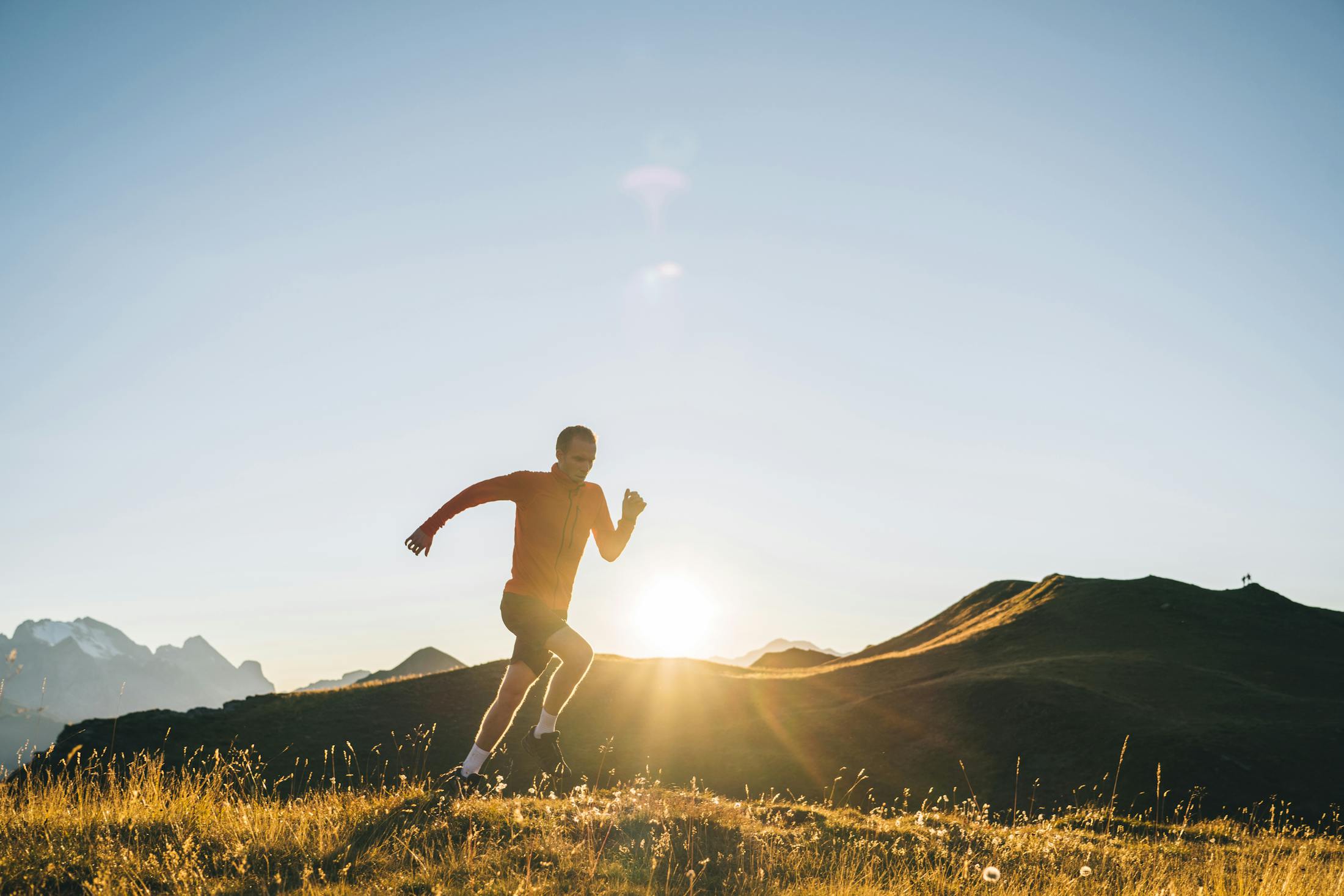 Man running in a meadow with the Sunset eluminating him in the background