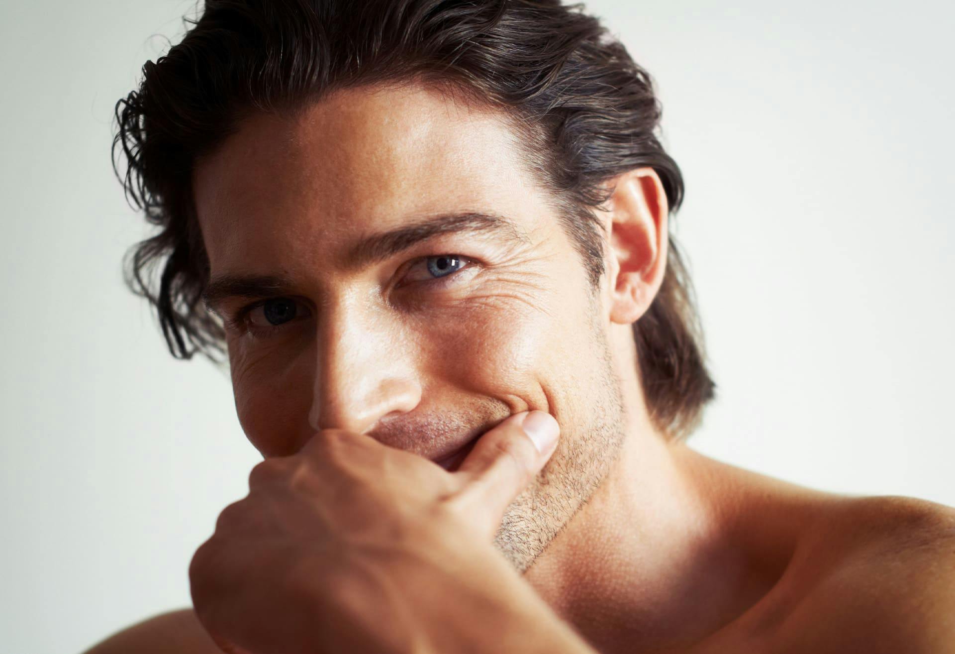 man smiling with his hand over his mouth