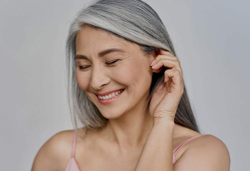Woman smiling and touching her ear