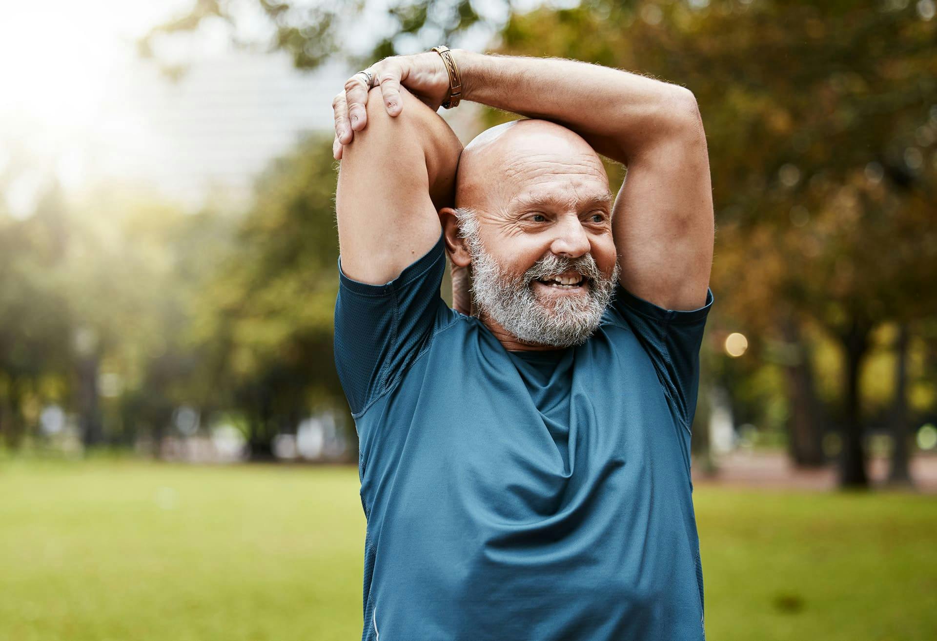 man smiling with his arms raised above his head as he stretches
