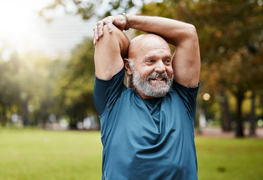 man smiling with his arms raised above his head as he stretches