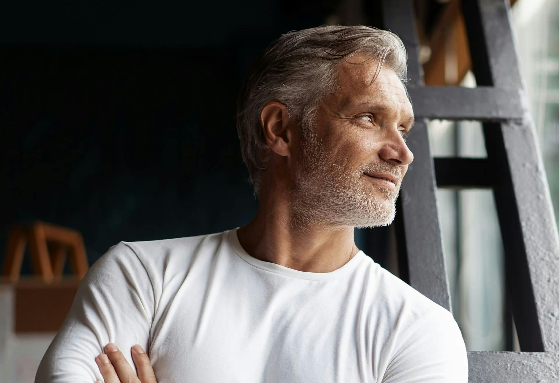 man crossing his arms while looking towards the window