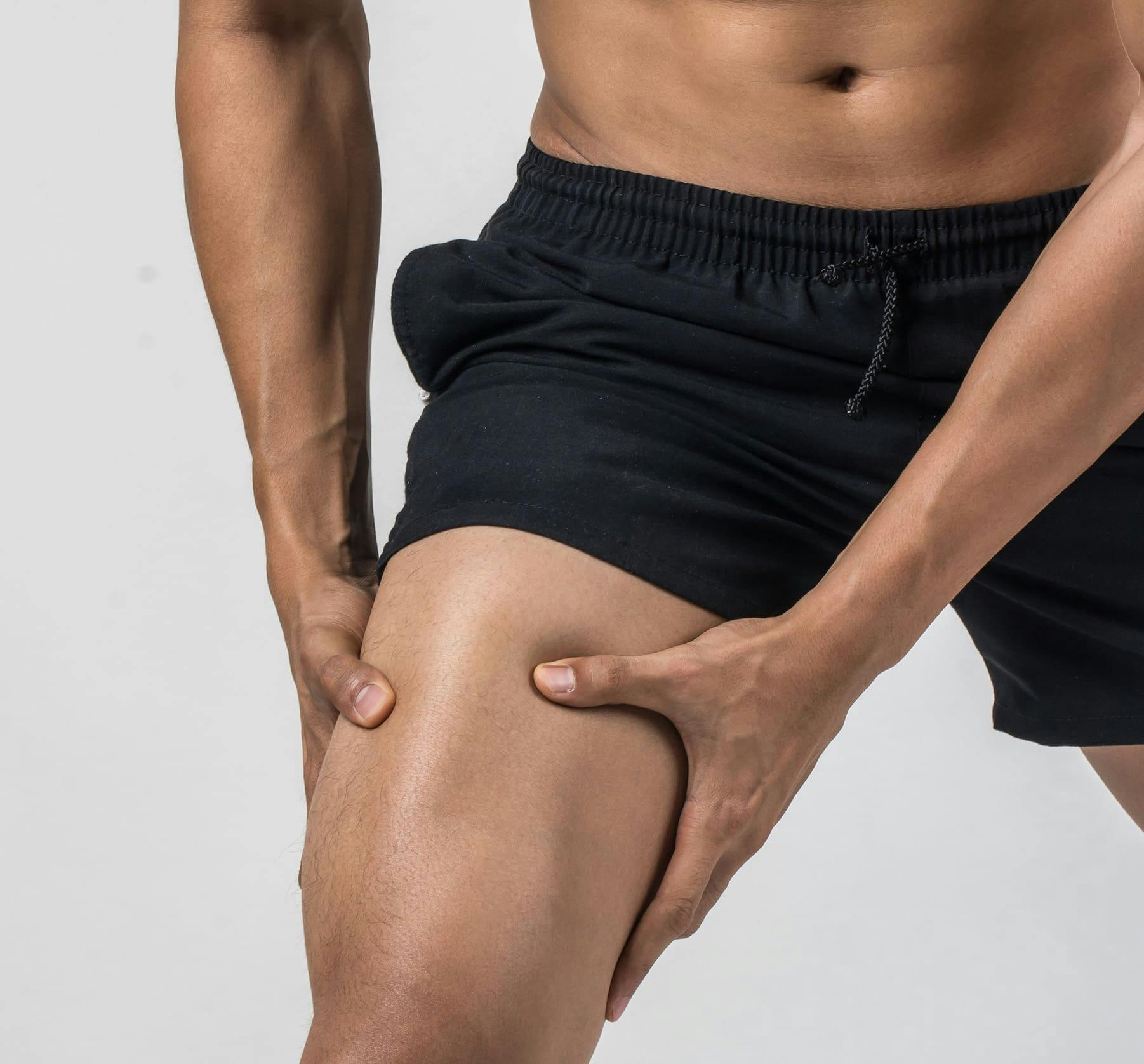 man grabbing his thigh muscle on either side