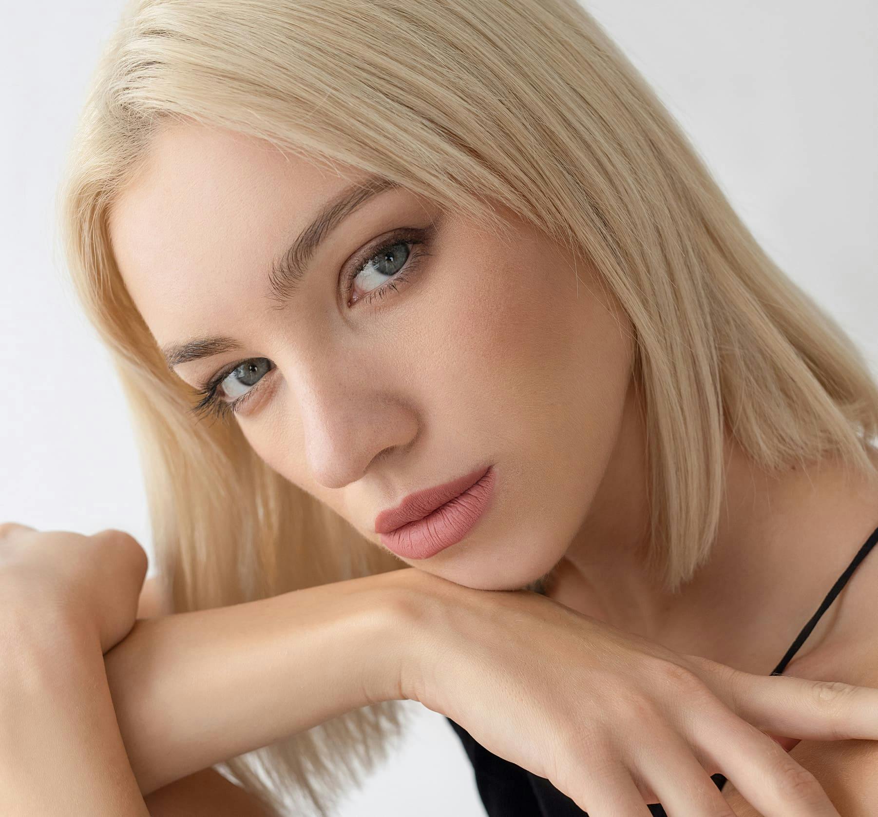 A blonde woman resting her chin on her arm