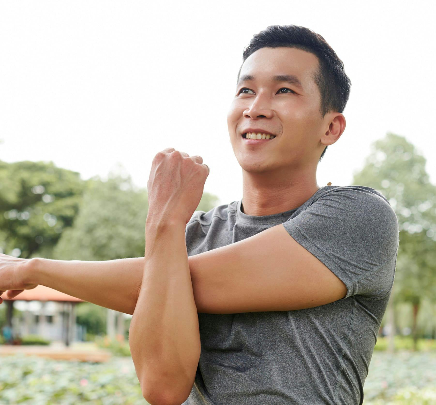 man stretching his left arm and using his other arm to hold it there