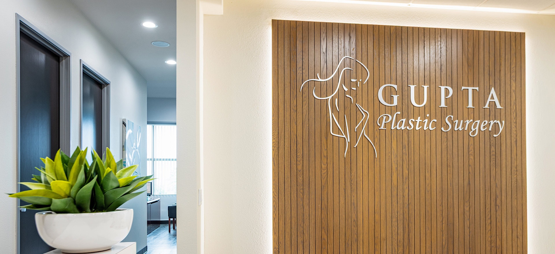 Waiting room of Gupta Plastic Surgery office showing logo on wall
