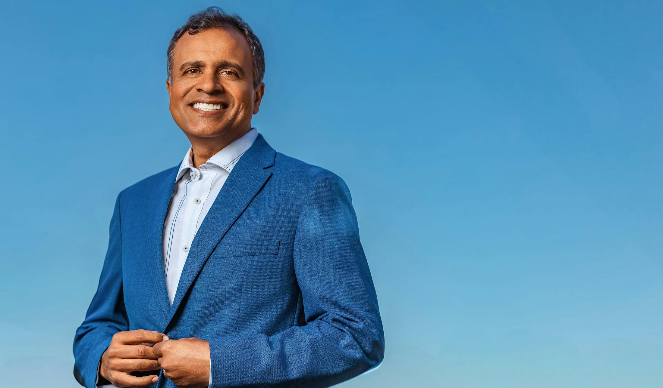 Dr. Gupta in blue suit and white undershirt smiling